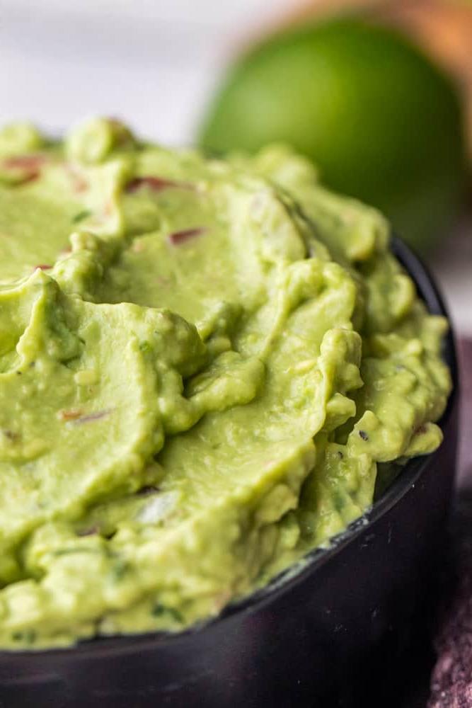 Close up image of guacamole dip in black bowl.