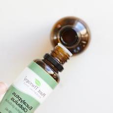 eucalyptus essential oil being added to a small glass amber dropper bottle