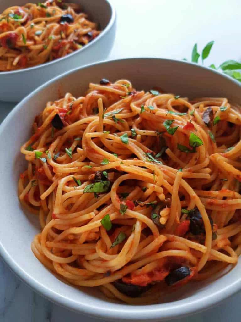 white bowl of spaghetti with red sauce 