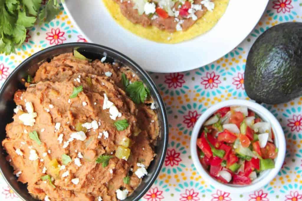 bowl of refried beans next to pico de Gallo