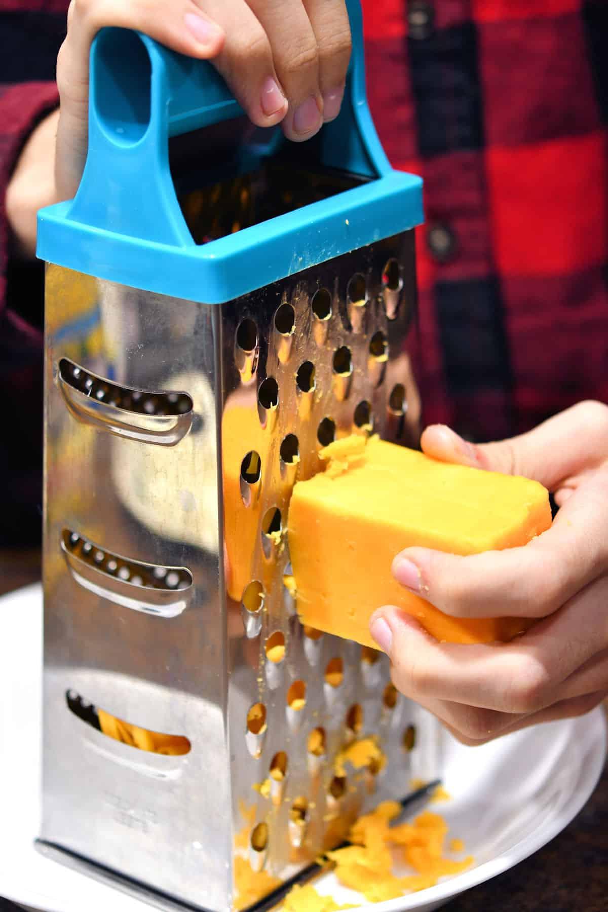 shredding cheddar cheese with a box grater